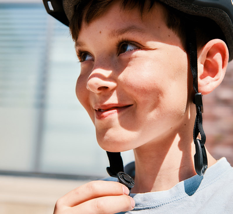 Boy wearing a helmet with a COINTRAP fastener which is opened