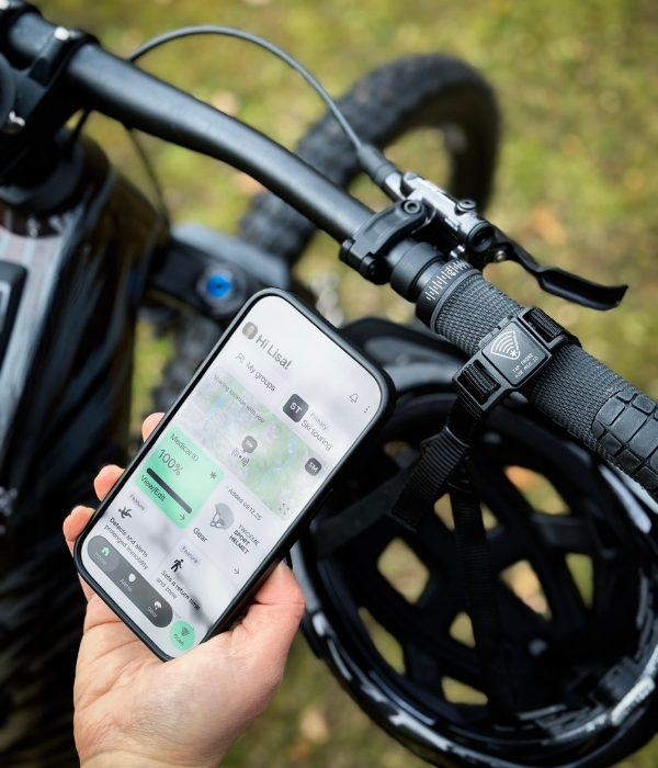 phone in hand with twiceme app next to FIDLOCK helmet buckle