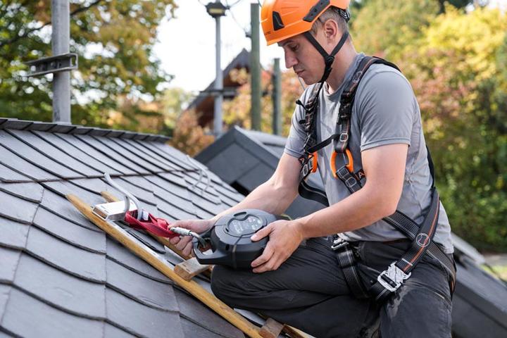 Arbeiter auf Dach, gesichert und mit Helm