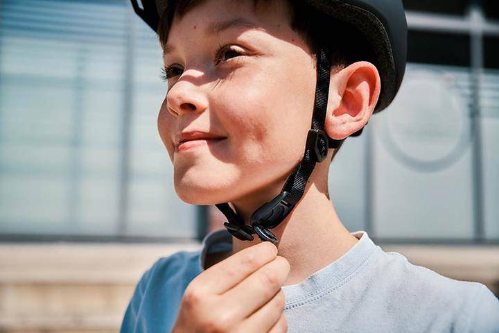 boy wearing a helmet with the FIDLOCK COINTRAP and opening it with one hand