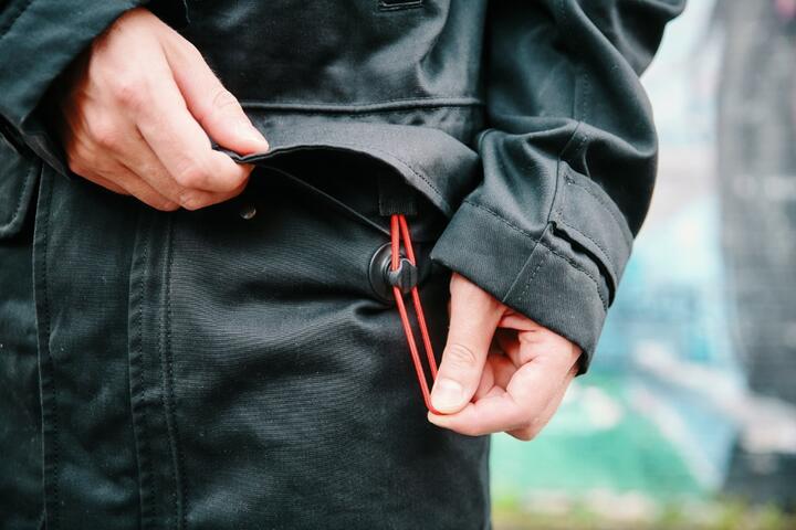 Man opening FIDLOCK buckle on black jacket 
