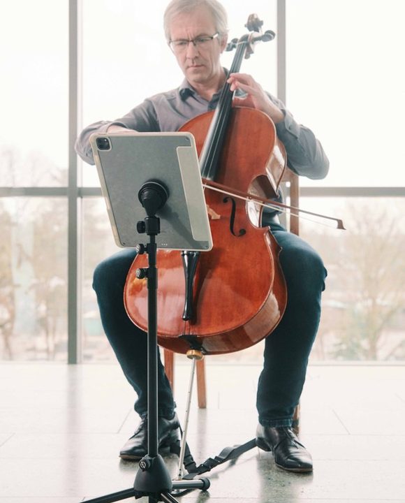 Violoncelliste lisant une partition sur un iPad fixé à un pied par VACUUM