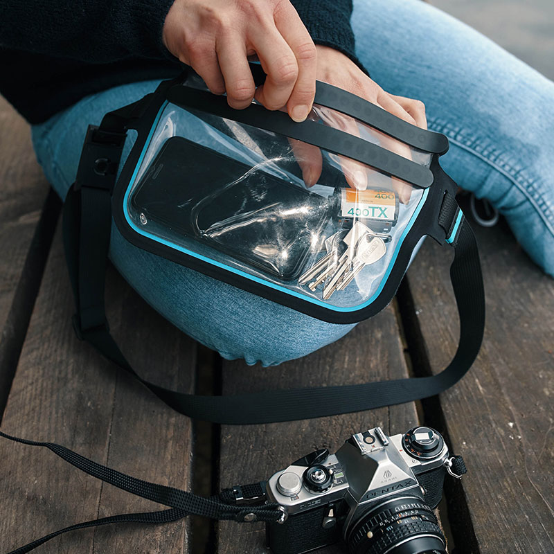 FIDLOCK-HERMETIC-sling-bag-transparent-outdoor-geöffnet-hand-holt-schlüssel-raus-photo-kontext