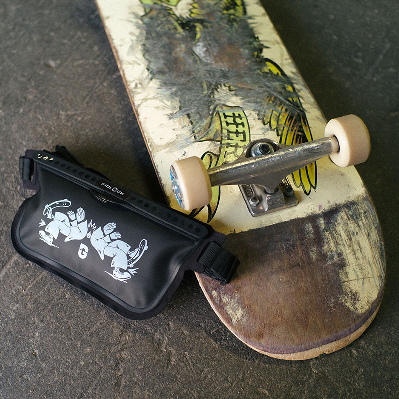FIDLOCK-HERMETIC-sling-bag-schwarz-Gleis-D-Skateboard-liegend-Rollen-sichtbar